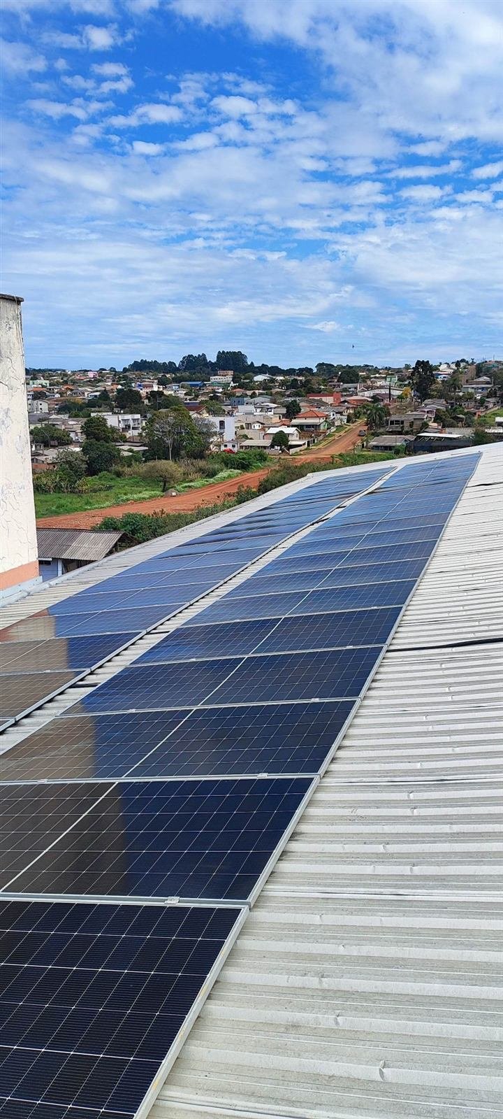 Painéis solares em telhado metálico com vista da cidade